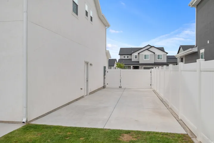 Concrete driveway with dual white vinyl privacy gates, bordered by a white vinyl fence