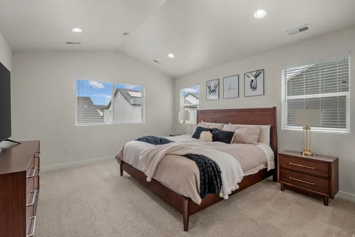 Vaulted ceilings, recessed lighting, carpet flooring, and multiple windows with blinds