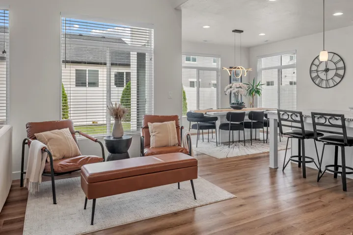 Open-concept living space featuring wood-finish flooring, abundant natural light, and a dining area with a modern chandelier