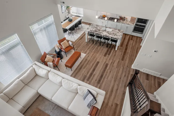 Open-concept living space featuring wood-finish flooring, a kitchen island with seating, white cabinetry, and recessed lighting