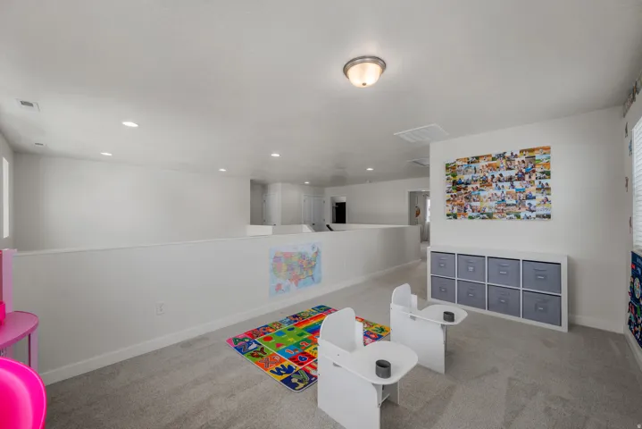 Carpeted upper level with recessed lighting, a built-in storage unit, and a window
