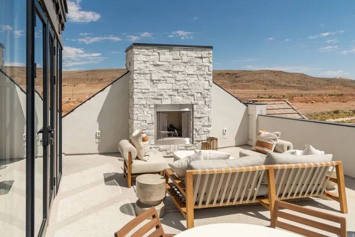 Rooftop patio with a stacked stone exterior fireplace, concrete flooring, and glass panel doors