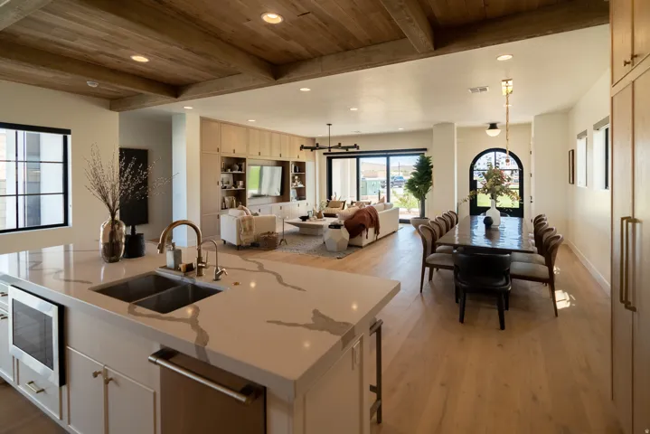 Kitchen island with integrated microwave and stainless steel sink, wood-finish flooring, wood-beamed ceilings, built-in entertainment cabinetry, and arched entry door