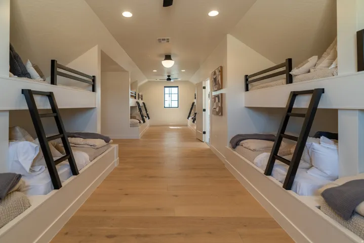 Built-in bunk beds with black ladders, wood-finish flooring, recessed lighting, and a ceiling fan