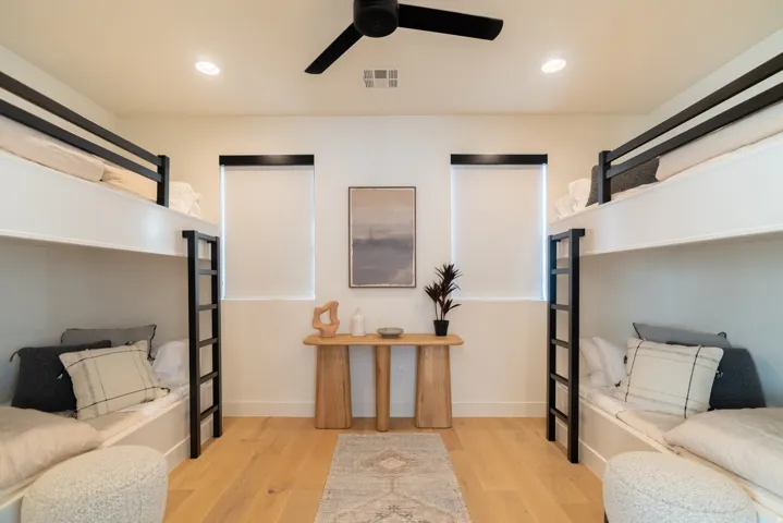 Recessed lighting, wood-finish flooring, two sets of built-in bunk beds with ladders, and a ceiling fan