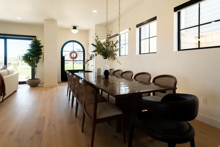 Light wood-finish flooring, arched entry door with glass panels, multiple transom windows, and a linear overhead light fixture