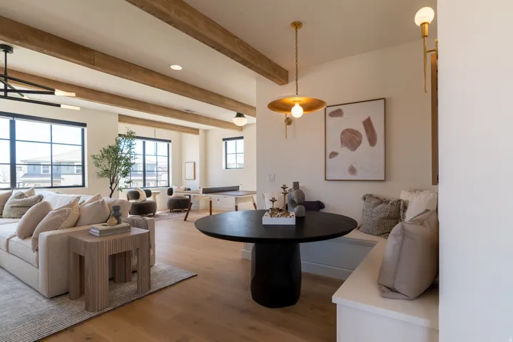 Spacious interior featuring exposed beam ceilings, large black-framed windows, and light wood-finish flooring