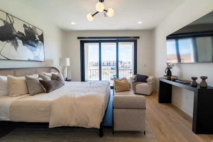 Spacious room with wood-finish flooring, a contemporary chandelier, recessed lighting, and a full-light glass sliding door opening to a balcony with metal railings