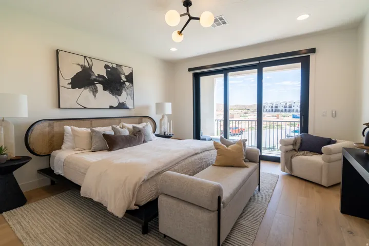 Light wood-finish flooring, a contemporary ceiling light fixture, recessed lighting, and a sliding glass door to an exterior balcony with metal railings