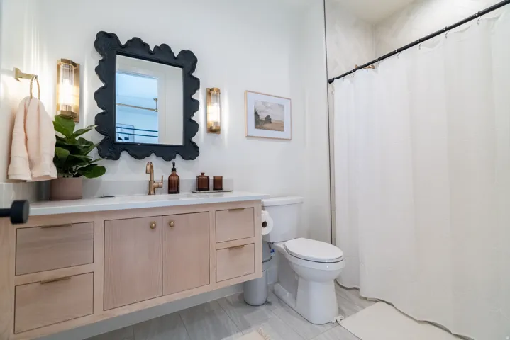 Light wood-finish vanity with ample storage, a white countertop, and gold-tone fixtures
