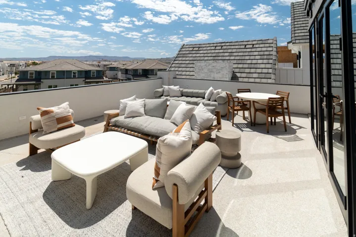 Expansive rooftop deck featuring a white perimeter wall, light-colored flooring, and large multi-pane glass doors
