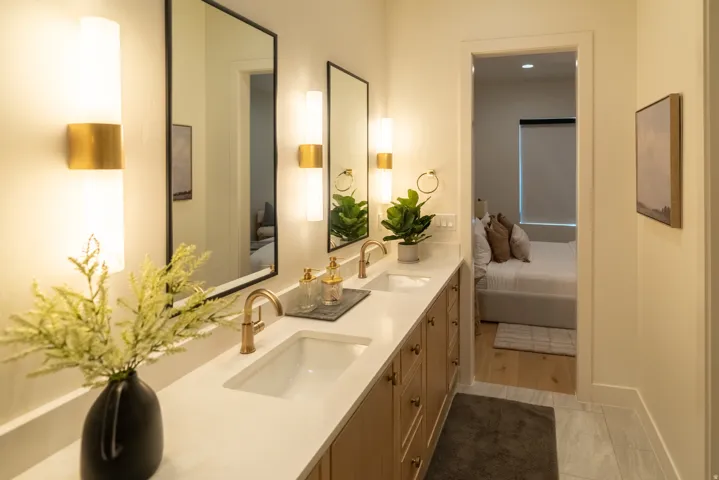 Double vanity with integrated sinks, framed mirrors, and wall-mounted sconces