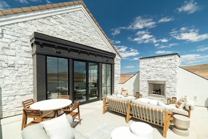 Spacious outdoor terrace with a stone-clad exterior, built-in fireplace, and expansive sliding glass doors