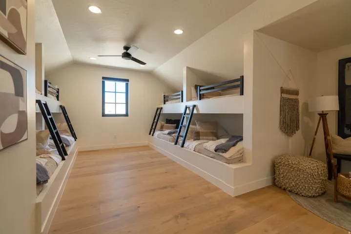 Built-in bunk beds with black ladders, wood-finish flooring, recessed lighting, and a ceiling fan