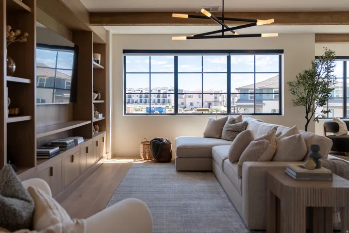 Built-in wood cabinetry with integrated shelving, large multi-pane windows, wood-finish flooring, and exposed wood ceiling beams