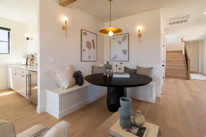 Built-in banquette seating with storage, wood-finish flooring, gold-tone lighting fixtures, and a built-in beverage refrigerator