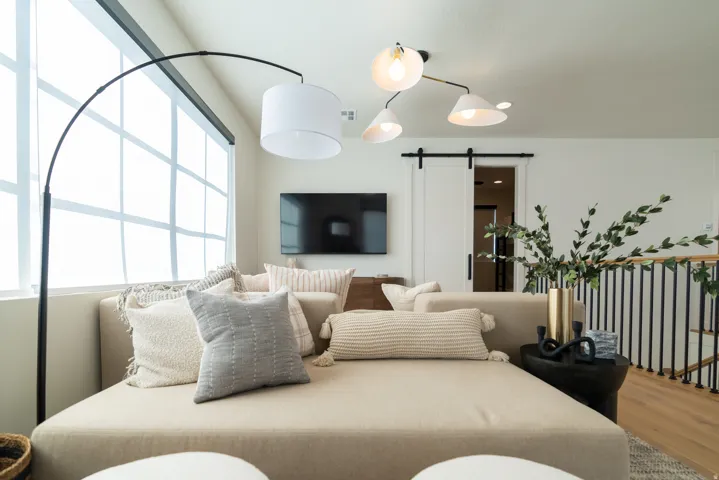 Large-pane windows, wood-finish flooring, a contemporary ceiling fixture, a sliding barn door, and a metal spindle railing