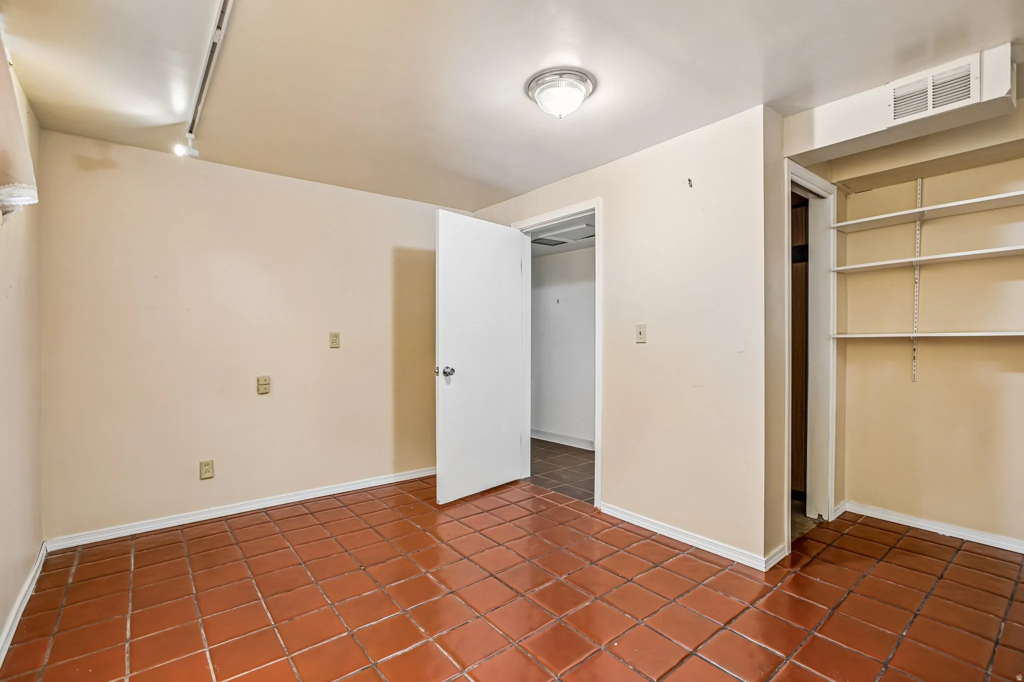 Tile flooring with a matte finish, built-in shelving, and track lighting