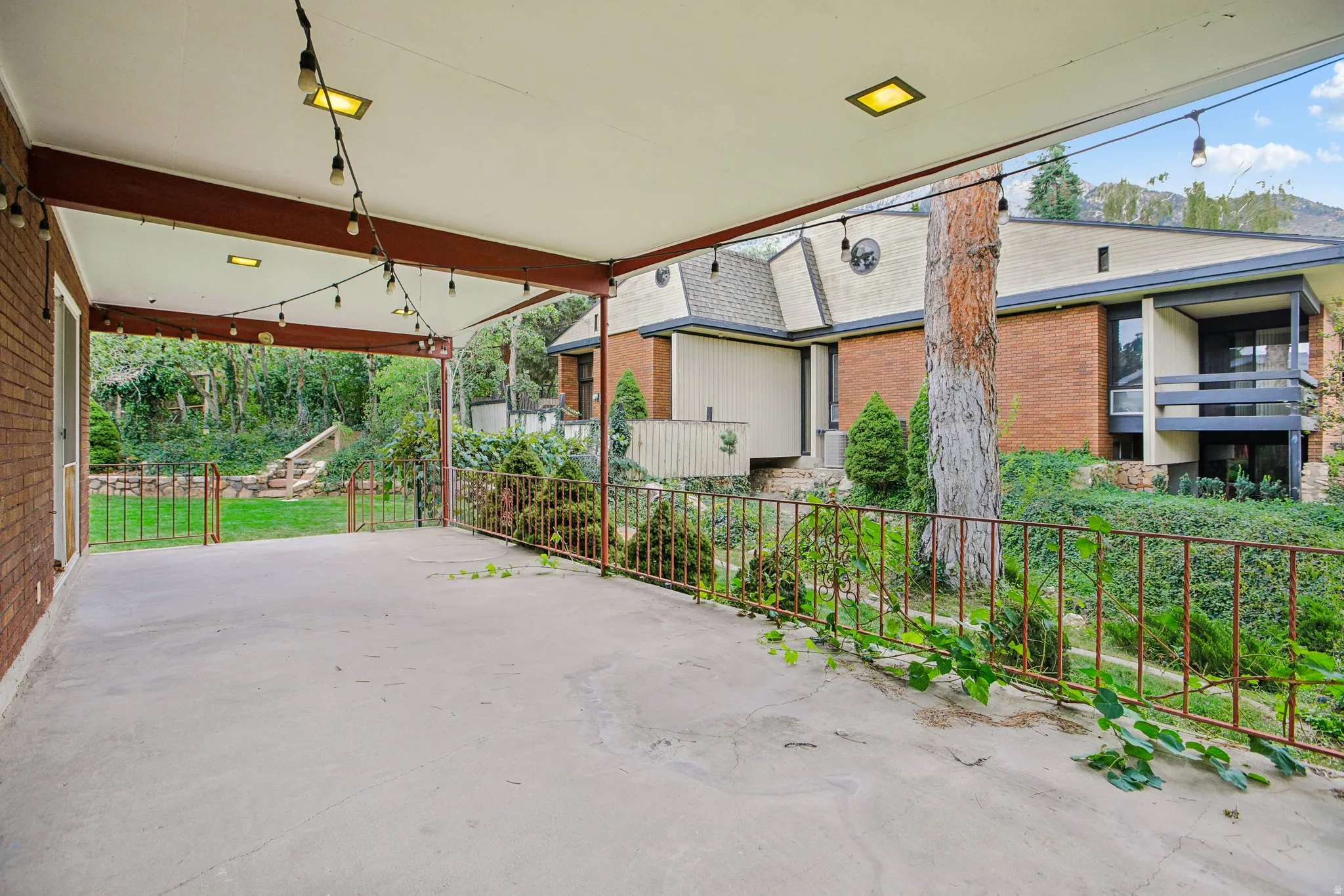 South East view from south patio.  Spacious covered patio with a concrete surface, featuring a brick exterior wall and a metal railing
