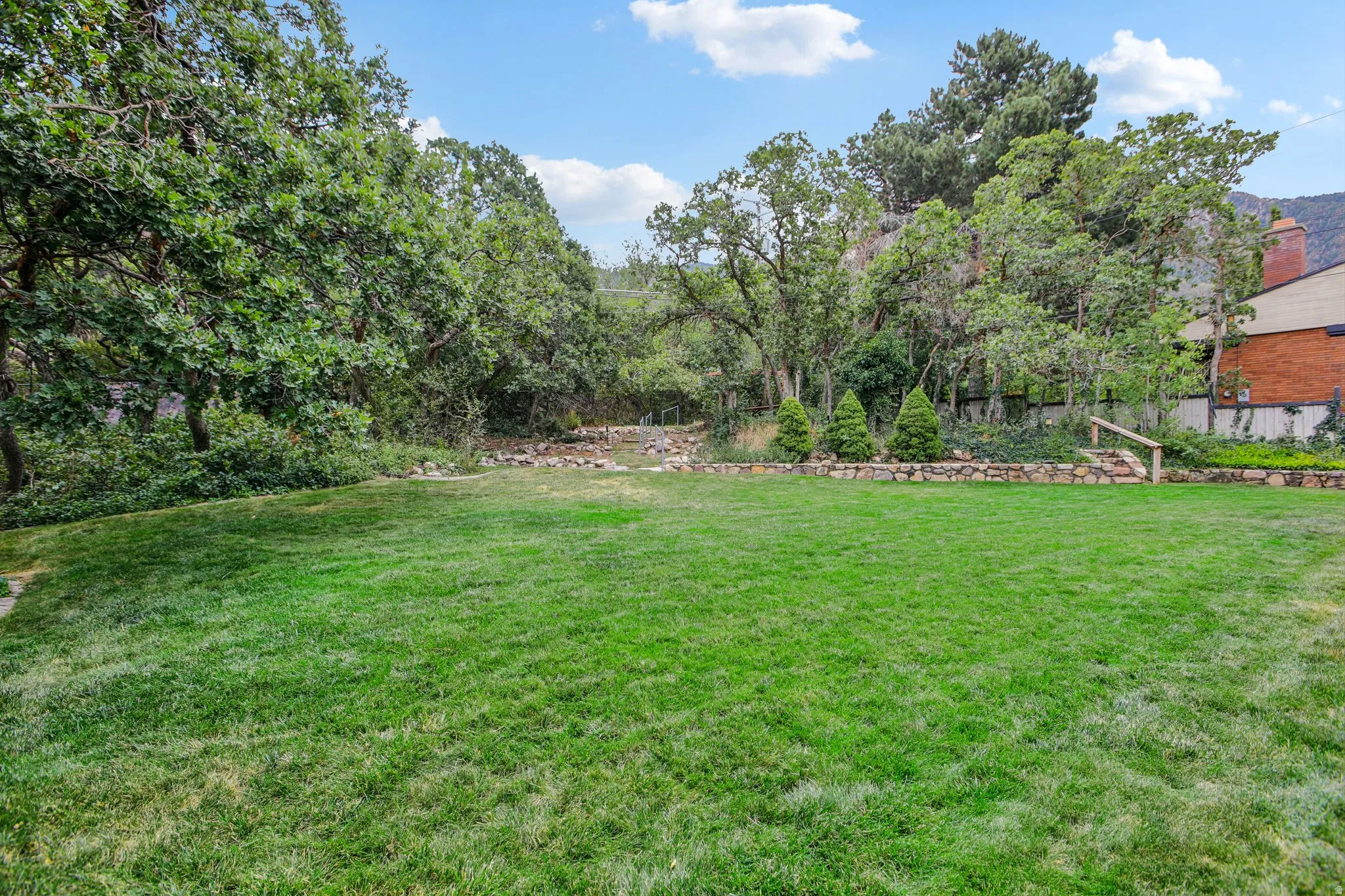 Expansive lawn with mature trees and a stone retaining wall