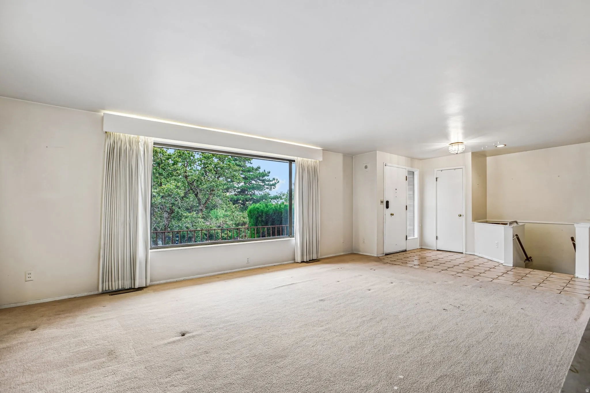 Expansive window with natural light, wall-to-wall carpeting, tiled entryway, and recessed lighting