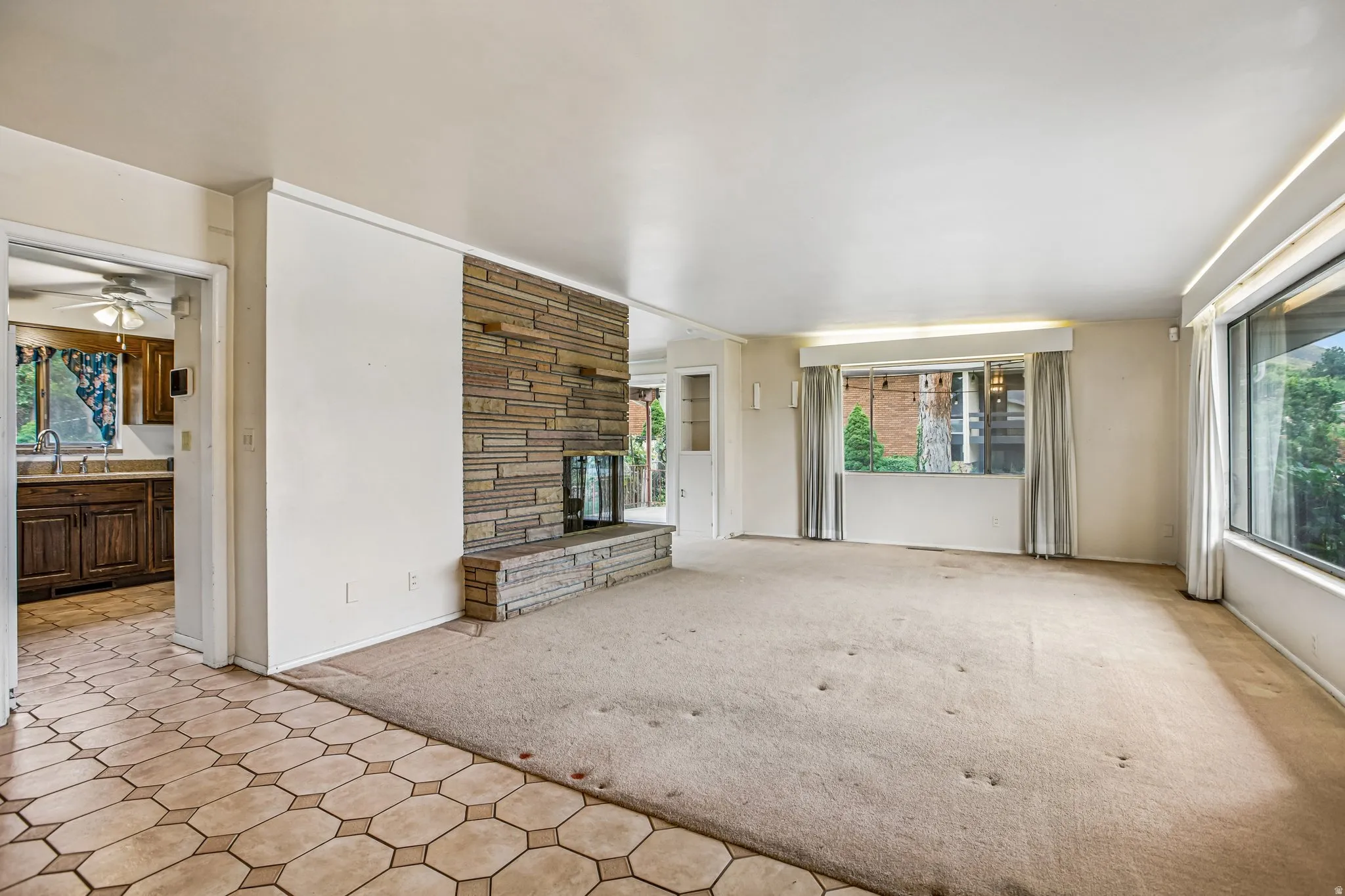 Stone fireplace with hearth, wall-to-wall carpeting, and a tile-patterned entry area