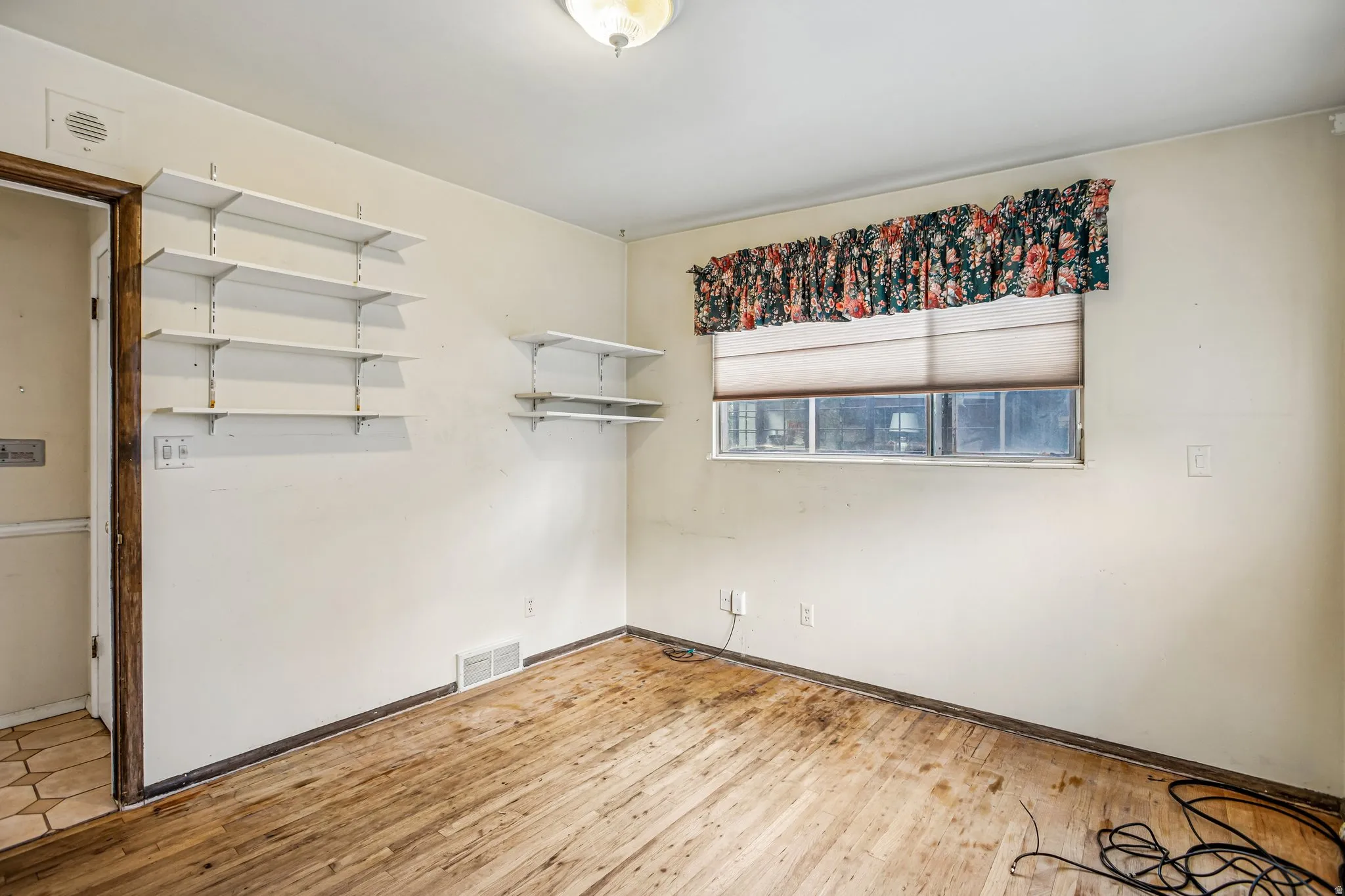 Wood-finish flooring, built-in shelving, window with blind, and ceiling-mounted light fixture
