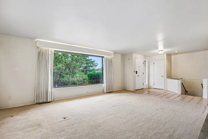 Expansive window with natural light, wall-to-wall carpeting, tiled entryway, and recessed lighting