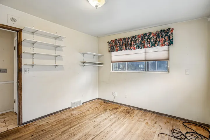 Wood-finish flooring, built-in shelving, window with blind, and ceiling-mounted light fixture