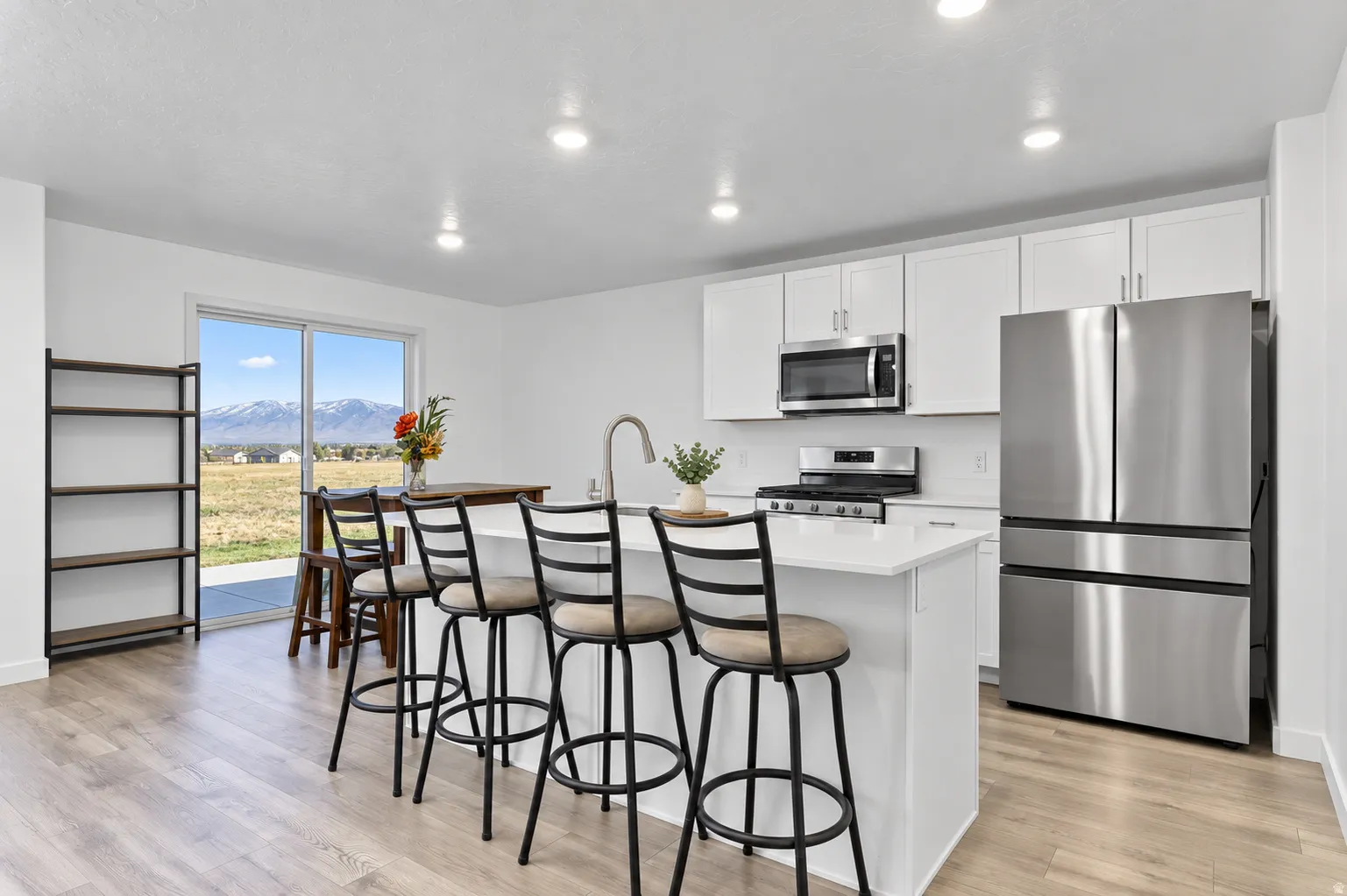 Modern kitchen featuring white cabinetry, stainless steel appliances, a center island with seating, recessed lighting, and wood-finish flooring