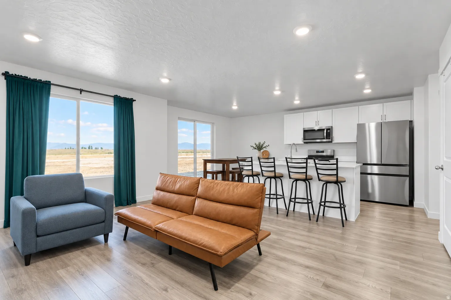 Open-concept living space with wood-finish flooring, recessed lighting, and large windows