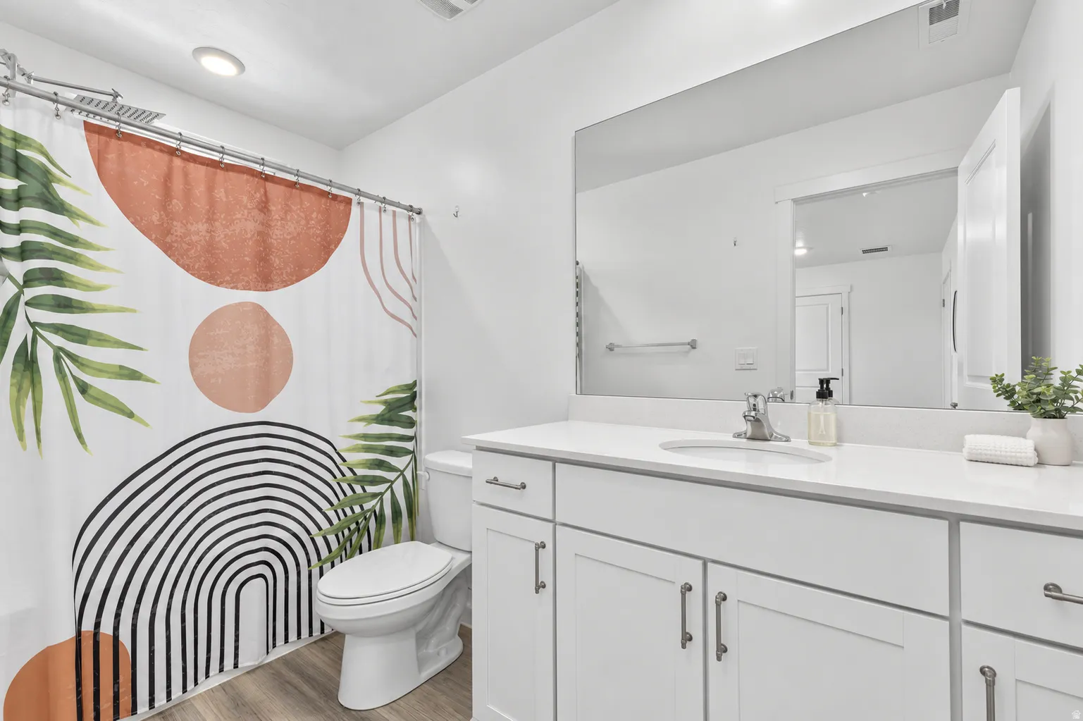 White vanity with undermount sink, expansive wall mirror, and modern cabinetry