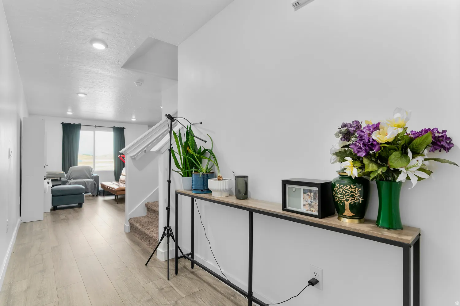 Recessed lighting illuminates the space, featuring wood-finish flooring and a staircase with carpeted treads