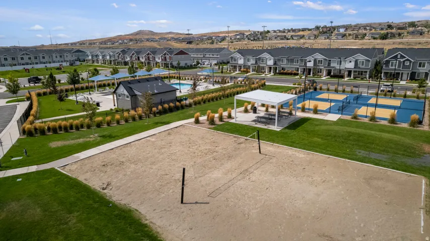 Sand volleyball court with a net, Pickleball courts, Swimming Pool bordered by green space and a concrete pathway