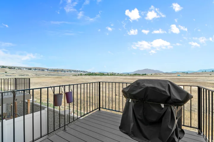 Expansive composite deck with metal railings overlooking open prairie landscape, featuring built-in grill with weather-protective cover and multiple storage solutions