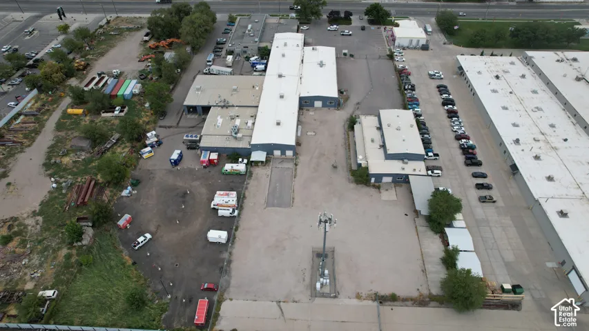 Multiple industrial buildings with metal roofs, extensive paved parking areas, and a concrete driveway