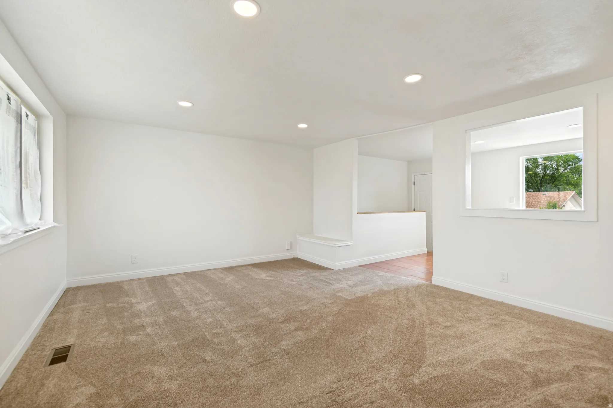Recessed lighting, neutral color palette, wood-finish flooring, half-wall partition, and an interior pass-through window