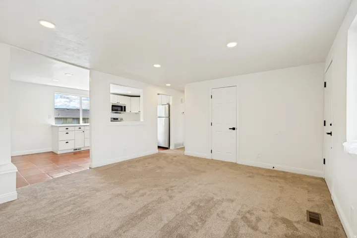 Recessed lighting, neutral carpeting, crisp white walls, and white paneled doors with matte black hardware