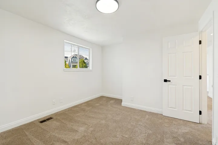 Carpeted flooring, white walls, white trim, recessed window, and a paneled interior door with matte black hardware