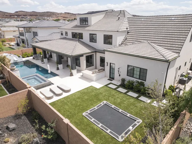 Stucco exterior with black-framed windows, tile roofing, private swimming pool, integrated spa, and expansive paved patio