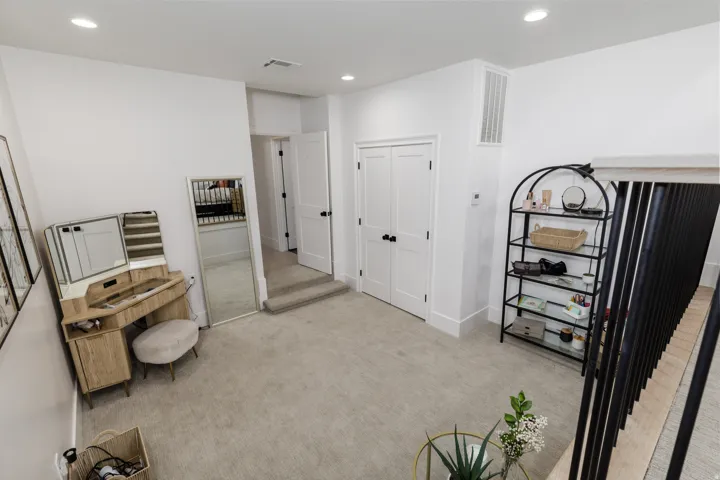 Carpeted floor with recessed lighting, white walls, and a white six-panel door with black hardware