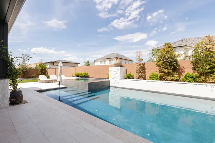 Expansive swimming pool with integrated spa and broad steps, surrounded by light-toned paving