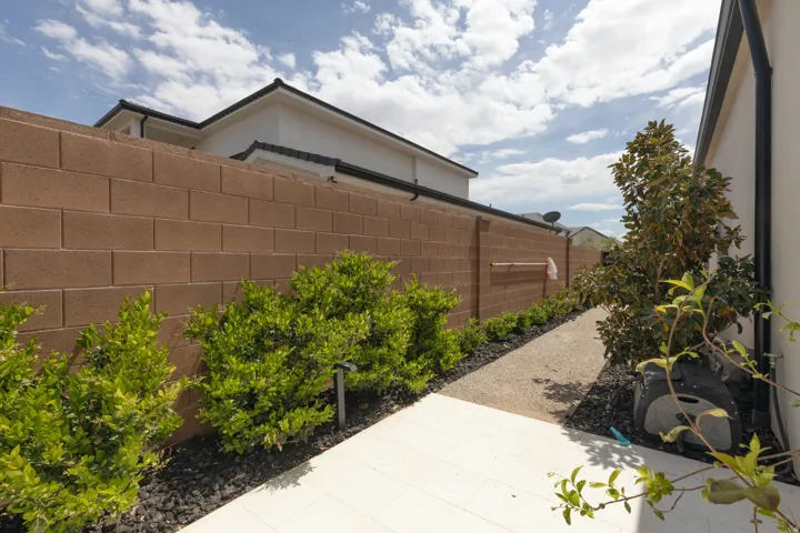 Paved walkway with surrounding landscaping, brick perimeter wall, and established plantings