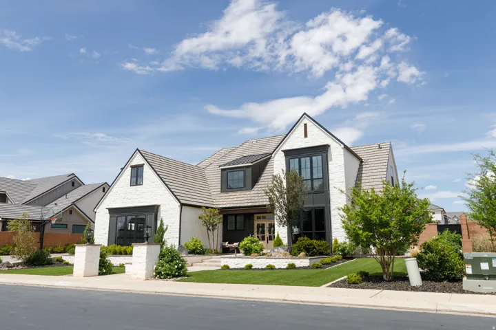 Two-story residence featuring white brick, dark-framed multi-pane windows, and a multi-gabled roofline