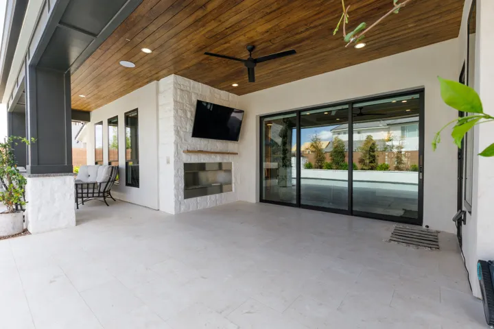 Covered patio with a stone-clad fireplace feature, wood-finish ceiling, recessed lighting, and a ceiling fan
