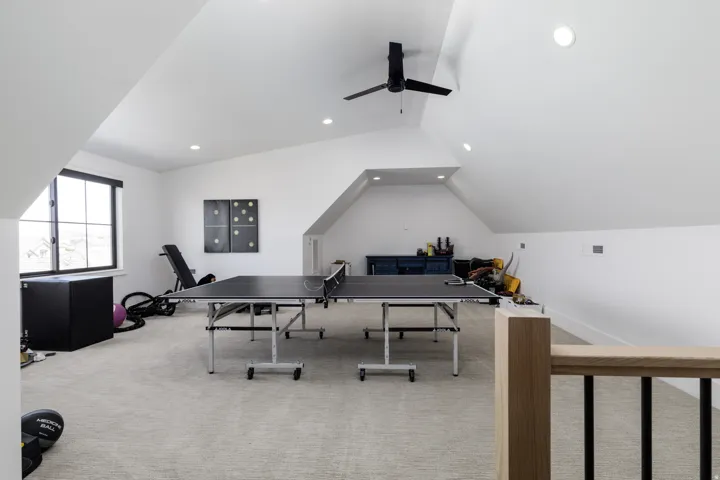 Carpeted loft space featuring sloped ceilings, recessed lighting, a ceiling fan, and a window with dark trim