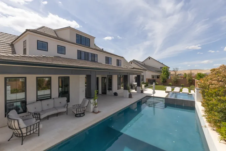 Expansive backyard featuring a rectangular pool with integrated spa, a spacious covered patio, and a manicured lawn