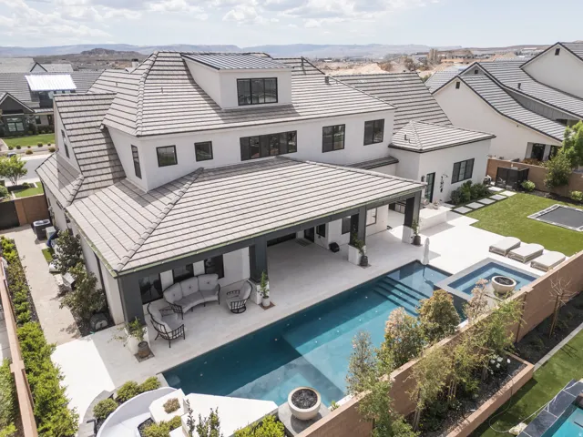 Multi-level residence with a tile roof, expansive swimming pool, integrated spa, covered patio, and a manicured lawn