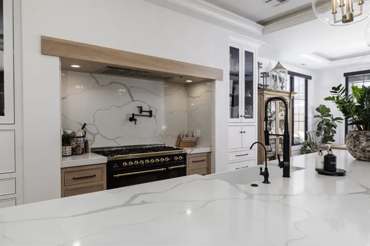 Gourmet kitchen with expansive stone countertops, professional-grade range, custom cabinetry, and built-in pot filler