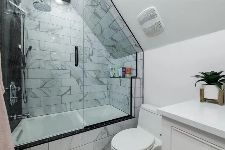 Bathtub shower with glass enclosure, subway tile surround, and a ceiling-mounted rain shower head